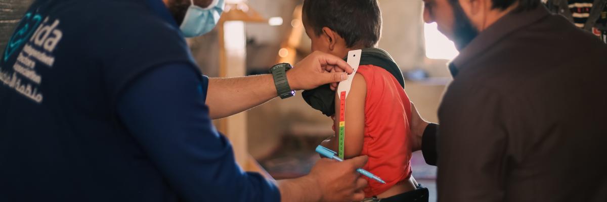 A doctor examines children's malnutrition inside a refugee camp. Malnutrition was measured using a mid-upper arm circumference belt. Aleppo, Syria
