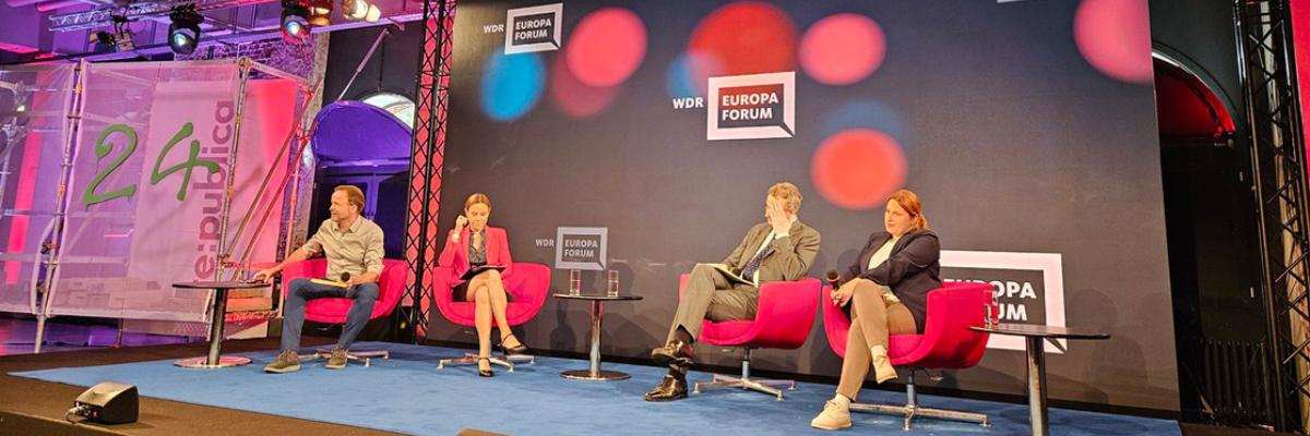 Image of a panel of people sat in chairs on a stage