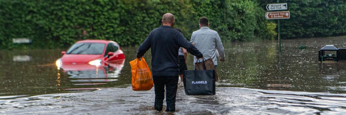 Two people walking through flooded street