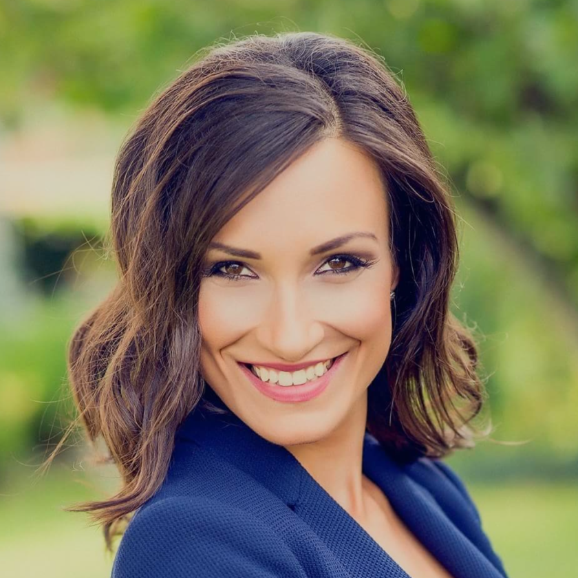 Image of a woman with long hair wearing a blue suit smiling at camera