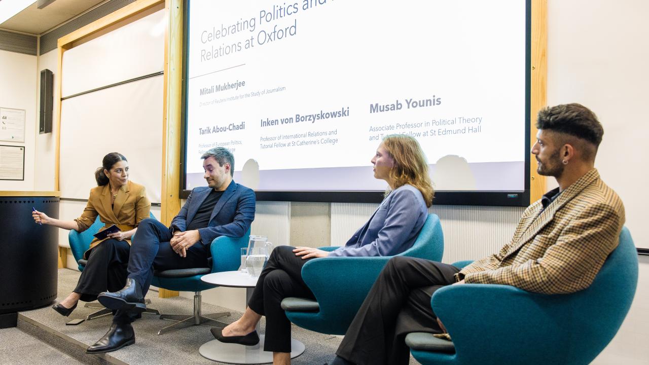 image of a panel of four people seated in front of a projector screen